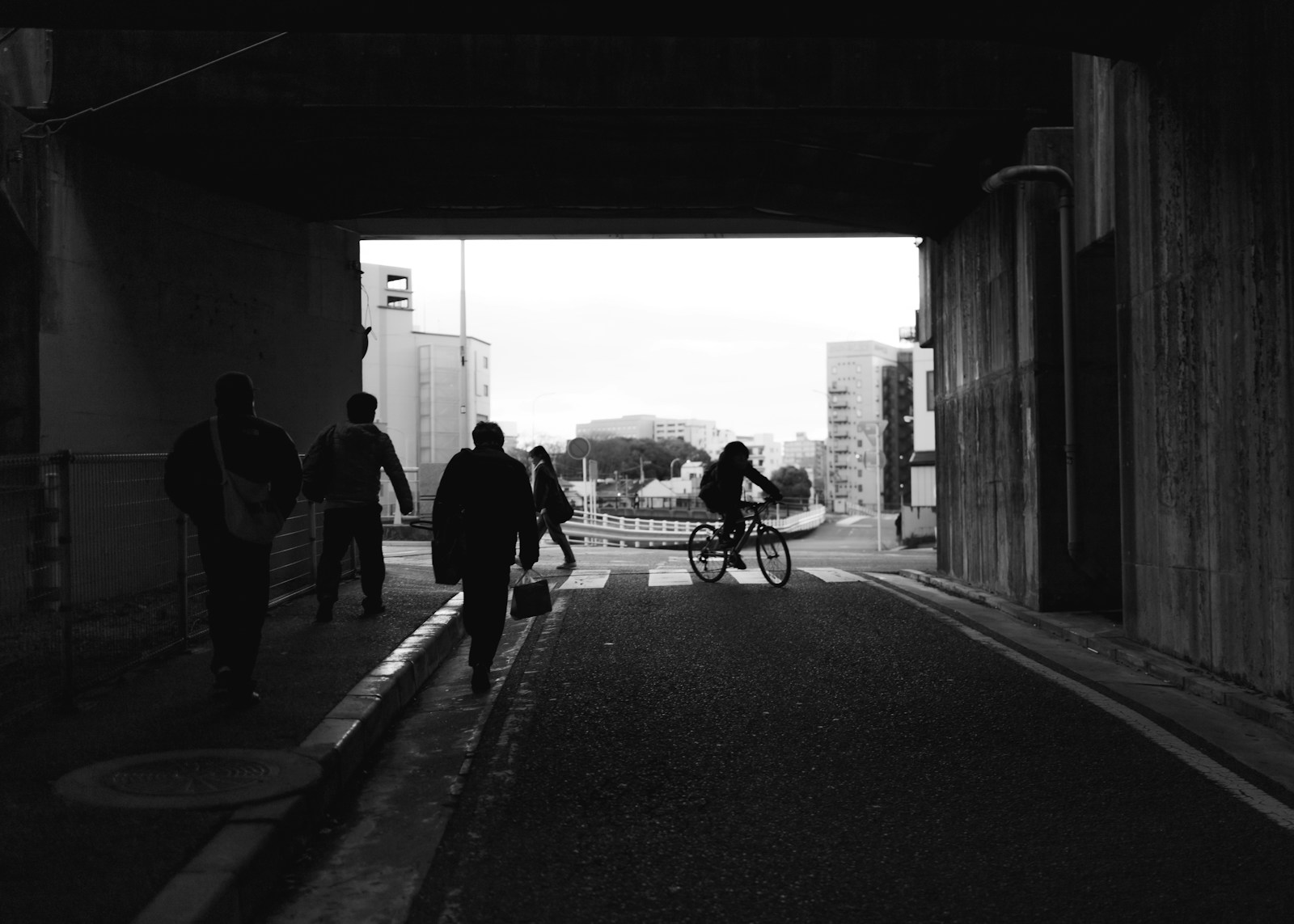 People walk and bike through an urban tunnel.